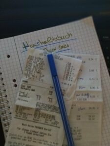 Kassenzettel und Haushaltsbuch mit Stift