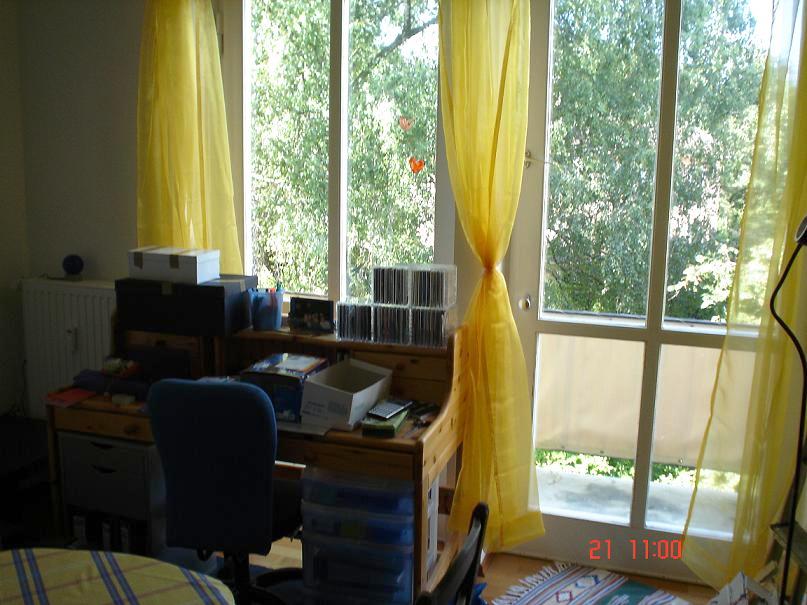 Zimmer mit Schreibtisch und Blick auf den Balkon ins Grüne